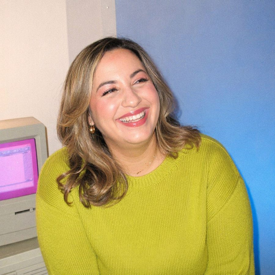 Audrey laughing next to a retro Macintosh, in a chartreuse sweater
